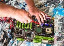 Επισκευή μιας μητρικής κάρτας PC με ένα κατσαβίδι με μια κόκκινη λαβή στοκ εικόνα με δικαίωμα ελεύθερης χρήσης Επισκευή μιας μητρικής κάρτας PC με ένα κατσαβίδι με μια κόκκινη λαβή στοκ εικόνα με δικαίωμα ελεύθερης χρήσης