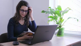 Επιχειρηματίας eyeglasses που κτυπά τη συνεδρίαση περιοδικών μπροστά από το φορητό προσωπικό υπολογιστή στην εργασία απόθεμα βίντεο Επιχειρηματίας eyeglasses που κτυπά τη συνεδρίαση περιοδικών μπροστά από το φορητό προσωπικό υπολογιστή στην εργασία απόθεμα βίντεο