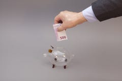 Επιχειρηματίας που βάζει πεντακόσια ευρώ στη piggy τράπεζα γυαλιού στοκ εικόνες Επιχειρηματίας που βάζει πεντακόσια ευρώ στη piggy τράπεζα γυαλιού στοκ εικόνες