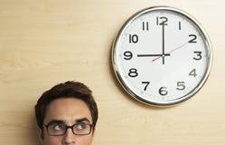 Επιχειρηματίας που εξετάζει το ρολόι στον ξύλινο τοίχο στην αρχή στοκ φωτογραφία με δικαίωμα ελεύθερης χρήσης Επιχειρηματίας που εξετάζει το ρολόι στον ξύλινο τοίχο στην αρχή στοκ φωτογραφία με δικαίωμα ελεύθερης χρήσης