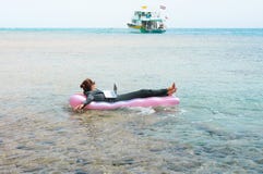 Επιχειρηματίας που επιπλέει στο lilo στη θάλασσα με το lap-top στοκ εικόνες Επιχειρηματίας που επιπλέει στο lilo στη θάλασσα με το lap-top στοκ εικόνες