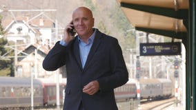 Επιχειρηματίας που περιμένει και που μιλά στο κινητό τηλέφωνο σε έναν σταθμό τρένου στοκ φωτογραφίες με δικαίωμα ελεύθερης χρήσης Επιχειρηματίας που περιμένει και που μιλά στο κινητό τηλέφωνο σε έναν σταθμό τρένου στοκ φωτογραφίες με δικαίωμα ελεύθερης χρήσης