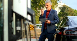 Επιχειρηματίας που χρησιμοποιεί την ψηφιακή ταμπλέτα μιλώντας στο κινητό τηλέφωνο στο σταθμό χρέωσης 4k φιλμ μικρού μήκους Επιχειρηματίας που χρησιμοποιεί την ψηφιακή ταμπλέτα μιλώντας στο κινητό τηλέφωνο στο σταθμό χρέωσης 4k φιλμ μικρού μήκους
