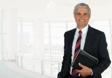 Επιχειρηματίας στο υψηλό βασικό γραφείο που θέτει το κράτημα ενός μικρού σημειωματάριου στοκ φωτογραφία με δικαίωμα ελεύθερης χρήσης Επιχειρηματίας στο υψηλό βασικό γραφείο που θέτει το κράτημα ενός μικρού σημειωματάριου στοκ φωτογραφία με δικαίωμα ελεύθερης χρήσης