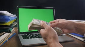 Επιχειρηματίας στον εργασιακό χώρο που μετρά πολλούς αμερικανικούς 100 λογαριασμούς με το lap-top με μια πράσινη οθόνη στο γραφεί Επιχειρηματίας στον εργασιακό χώρο που μετρά πολλούς αμερικανικούς 100 λογαριασμούς με το lap-top με μια πράσινη οθόνη στο γραφεί