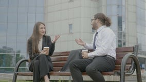 Επιχειρηματίες που κάθονται στον πάγκο μπροστά από την εταιρία που μιλά και που γελά κρατώντας τα φλυτζάνια καφέ στα χέρια τους απόθεμα βίντεο Επιχειρηματίες που κάθονται στον πάγκο μπροστά από την εταιρία που μιλά και που γελά κρατώντας τα φλυτζάνια καφέ στα χέρια τους απόθεμα βίντεο