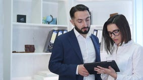 Επιχειρηματίες που χρησιμοποιούν τον υπολογιστή ταμπλετών με τη γυναίκα συνάδελφος στο υπόβαθρο στο γραφείο απόθεμα βίντεο Επιχειρηματίες που χρησιμοποιούν τον υπολογιστή ταμπλετών με τη γυναίκα συνάδελφος στο υπόβαθρο στο γραφείο απόθεμα βίντεο