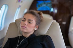 Επιχειρησιακή γυναίκα σε ένα εταιρικό αεριωθούμενο αεροπλάνο που χαλαρώνει και που ακούει το musi Στοκ εικόνες με δικαίωμα ελεύθερης χρήσης Επιχειρησιακή γυναίκα σε ένα εταιρικό αεριωθούμενο αεροπλάνο που χαλαρώνει και που ακούει το musi Στοκ εικόνες με δικαίωμα ελεύθερης χρήσης