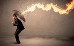 Επιχειρησιακό άτομο που υπερασπίζεται από ένα βέλος πυρκαγιάς με μια ομπρέλα στοκ εικόνες Επιχειρησιακό άτομο που υπερασπίζεται από ένα βέλος πυρκαγιάς με μια ομπρέλα στοκ εικόνες