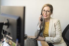 Εργαζόμενη γυναίκα γραφείων που εξετάζει τη κάμερα στην αρχή στοκ εικόνες Εργαζόμενη γυναίκα γραφείων που εξετάζει τη κάμερα στην αρχή στοκ εικόνες