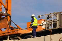 Εργαζόμενος στον κίτρινο και πορτοκαλή γερανό στο εργοτάξιο οικοδομής στοκ φωτογραφίες Εργαζόμενος στον κίτρινο και πορτοκαλή γερανό στο εργοτάξιο οικοδομής στοκ φωτογραφίες