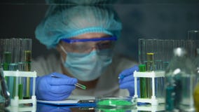 Ερευνητής αριστεροχείρων που προσθέτει την πράσινη σκόνη στο σωλήνα και που κάνει τις σημειώσεις, πείραμα απόθεμα βίντεο Ερευνητής αριστεροχείρων που προσθέτει την πράσινη σκόνη στο σωλήνα και που κάνει τις σημειώσεις, πείραμα απόθεμα βίντεο