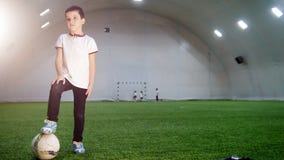 Εσωτερικός χώρος ποδοσφαίρου Ένα μικρό αγόρι που στέκεται με την τοποθέτηση του ποδιού στη σφαίρα απόθεμα βίντεο Εσωτερικός χώρος ποδοσφαίρου Ένα μικρό αγόρι που στέκεται με την τοποθέτηση του ποδιού στη σφαίρα απόθεμα βίντεο