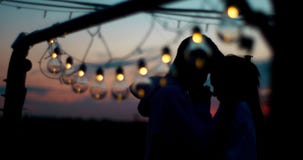 Ευαίσθητο πορτρέτο δύο cilhouettes ζευγών που στέκεται πίσω από τη σειρά των φω'των κατά τη διάρκεια του ηλιοβασιλέματος Ο τύπος απόθεμα βίντεο Ευαίσθητο πορτρέτο δύο cilhouettes ζευγών που στέκεται πίσω από τη σειρά των φω'των κατά τη διάρκεια του ηλιοβασιλέματος Ο τύπος απόθεμα βίντεο