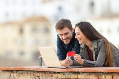 Ευτυχές ζεύγος που πληρώνει on-line με την πιστωτική κάρτα και το lap-top στοκ εικόνα Ευτυχές ζεύγος που πληρώνει on-line με την πιστωτική κάρτα και το lap-top στοκ εικόνα