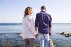Ευτυχές ζεύγος που στέκεται σε μια αποβάθρα θάλασσας Μοντέρνο ζεύγος, χέρι εκμετάλλευσης, σγουρή τρίχα, άσπρο πουκάμισο, αιτιώδης στοκ εικόνα Ευτυχές ζεύγος που στέκεται σε μια αποβάθρα θάλασσας Μοντέρνο ζεύγος, χέρι εκμετάλλευσης, σγουρή τρίχα, άσπρο πουκάμισο, αιτιώδης στοκ εικόνα