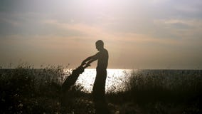 Ευτυχές παιχνίδι πατέρων και γιων σκιαγραφιών στην παραλία στο ηλιοβασίλεμα Μπαμπάς που κρατά τα χέρια παιδιών του που περιστρέφο Ευτυχές παιχνίδι πατέρων και γιων σκιαγραφιών στην παραλία στο ηλιοβασίλεμα Μπαμπάς που κρατά τα χέρια παιδιών του που περιστρέφο
