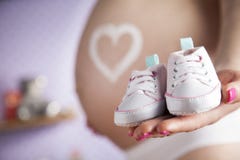 Ευτυχής έγκυος γυναίκα, παπούτσια μωρών στα χέρια της στοκ εικόνες με δικαίωμα ελεύθερης χρήσης Ευτυχής έγκυος γυναίκα, παπούτσια μωρών στα χέρια της στοκ εικόνες με δικαίωμα ελεύθερης χρήσης