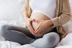 Ευτυχής έγκυος γυναίκα που κάνει τη χειρονομία καρδιών στο κρεβάτι στοκ φωτογραφίες Ευτυχής έγκυος γυναίκα που κάνει τη χειρονομία καρδιών στο κρεβάτι στοκ φωτογραφίες