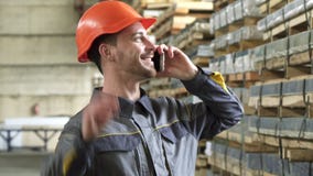 Ευτυχής βιομηχανικός εργάτης σε ένα hardhat χαμόγελο που μιλά στο τηλέφωνο φιλμ μικρού μήκους Ευτυχής βιομηχανικός εργάτης σε ένα hardhat χαμόγελο που μιλά στο τηλέφωνο φιλμ μικρού μήκους