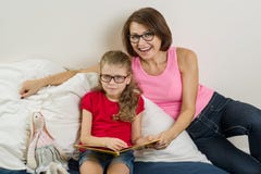 Ευτυχής γυναίκα με το παιδί κορών της, που διαβάζει μαζί ένα βιβλίο στο σπίτι στοκ εικόνα Ευτυχής γυναίκα με το παιδί κορών της, που διαβάζει μαζί ένα βιβλίο στο σπίτι στοκ εικόνα