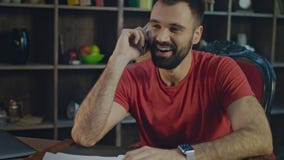 Ευτυχής επιχειρηματίας που μιλά το κινητό τηλέφωνο στον εγχώριο εργασιακό χώρο Επιχειρησιακή συνομιλία φιλμ μικρού μήκους Ευτυχής επιχειρηματίας που μιλά το κινητό τηλέφωνο στον εγχώριο εργασιακό χώρο Επιχειρησιακή συνομιλία φιλμ μικρού μήκους