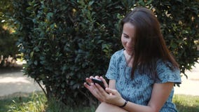 Ευτυχής θερινή συνεδρίαση brunette γυναικών νέων κοριτσιών υπαίθρια στο πάρκο, που χρησιμοποιεί το κινητό τηλέφωνο με τον ήχο AI απόθεμα βίντεο Ευτυχής θερινή συνεδρίαση brunette γυναικών νέων κοριτσιών υπαίθρια στο πάρκο, που χρησιμοποιεί το κινητό τηλέφωνο με τον ήχο AI απόθεμα βίντεο