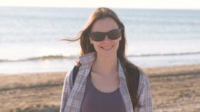Ευτυχής νέα χαμογελώντας γυναίκα brunette στα γυαλιά ηλίου στην παραλία άμμου θαλασσίως φιλμ μικρού μήκους Ευτυχής νέα χαμογελώντας γυναίκα brunette στα γυαλιά ηλίου στην παραλία άμμου θαλασσίως φιλμ μικρού μήκους