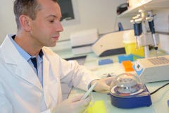 Ευτυχής νέος αρσενικός ερευνητής που εργάζεται στο εργαστήριο στοκ φωτογραφίες Ευτυχής νέος αρσενικός ερευνητής που εργάζεται στο εργαστήριο στοκ φωτογραφίες