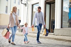 Ευτυχής οικογένεια με τις τσάντες παιδιών και αγορών στην πόλη στοκ φωτογραφίες Ευτυχής οικογένεια με τις τσάντες παιδιών και αγορών στην πόλη στοκ φωτογραφίες