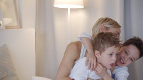 Ευτυχής οικογένεια - μητέρα με δύο γιους που αγκαλιάζουν στο κρεβάτι απόθεμα βίντεο Ευτυχής οικογένεια - μητέρα με δύο γιους που αγκαλιάζουν στο κρεβάτι απόθεμα βίντεο