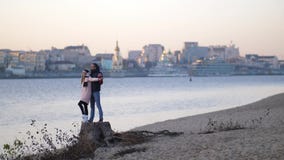 Ευτυχής τύπος και αγκάλιασμα και ρολόι κοριτσιών στην απόσταση Η λαβή μεταξύ τους δίνει και χαμόγελο Παραλία 4K η αργή Mo φθινοπώ απόθεμα βίντεο Ευτυχής τύπος και αγκάλιασμα και ρολόι κοριτσιών στην απόσταση Η λαβή μεταξύ τους δίνει και χαμόγελο Παραλία 4K η αργή Mo φθινοπώ απόθεμα βίντεο