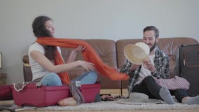 Ευτυχείς άνδρας και γυναίκα πορτρέτου στο πάτωμα στο σπίτι μπροστά από τον καναπέ δέρματος, που συσκευάζει μια βαλίτσα πριν από τ απόθεμα βίντεο Ευτυχείς άνδρας και γυναίκα πορτρέτου στο πάτωμα στο σπίτι μπροστά από τον καναπέ δέρματος, που συσκευάζει μια βαλίτσα πριν από τ απόθεμα βίντεο