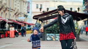 Ευτυχείς μητέρα και αυτή λίγος γιος που περπατά και που γελά στην πόλη Ευτυχείς μητέρα και αυτή λίγος γιος που περπατά και που γελά στην πόλη