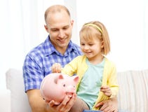Ευτυχείς πατέρας και κόρη με τη μεγάλη piggy τράπεζα στοκ φωτογραφία με δικαίωμα ελεύθερης χρήσης Ευτυχείς πατέρας και κόρη με τη μεγάλη piggy τράπεζα στοκ φωτογραφία με δικαίωμα ελεύθερης χρήσης