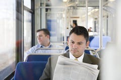 Εφημερίδα ανάγνωσης επιχειρηματιών στο τραίνο στοκ εικόνα Εφημερίδα ανάγνωσης επιχειρηματιών στο τραίνο στοκ εικόνα