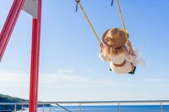 Εύθυμο κορίτσι σε ένα καπέλο και ένα φόρεμα που οδηγούν σε μια ταλάντευση που αγνοεί τη θάλασσα στοκ φωτογραφία Εύθυμο κορίτσι σε ένα καπέλο και ένα φόρεμα που οδηγούν σε μια ταλάντευση που αγνοεί τη θάλασσα στοκ φωτογραφία