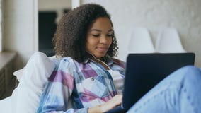 Εύθυμο μικτό κορίτσι φυλών που έχει την τηλεοπτική συνομιλία με τους φίλους που χρησιμοποιούν τη κάμερα lap-top στο κρεβάτι απόθεμα βίντεο Εύθυμο μικτό κορίτσι φυλών που έχει την τηλεοπτική συνομιλία με τους φίλους που χρησιμοποιούν τη κάμερα lap-top στο κρεβάτι απόθεμα βίντεο