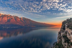 Ζαλίζοντας ηλιοβασίλεμα στη λίμνη Garda Άποψη των χιονωδών Άλπεων που χρωματίζονται από τον ήλιο ρύθμισης από τον απότομο βράχο τ στοκ φωτογραφίες Ζαλίζοντας ηλιοβασίλεμα στη λίμνη Garda Άποψη των χιονωδών Άλπεων που χρωματίζονται από τον ήλιο ρύθμισης από τον απότομο βράχο τ στοκ φωτογραφίες