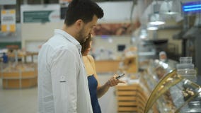 Ζεύγος της Νίκαιας των νέων, του άνδρα και της γυναίκας στην υπεραγορά που επιλέγει τη βιομηχανία ζαχαρωδών προϊόντων απόθεμα βίντεο Ζεύγος της Νίκαιας των νέων, του άνδρα και της γυναίκας στην υπεραγορά που επιλέγει τη βιομηχανία ζαχαρωδών προϊόντων απόθεμα βίντεο