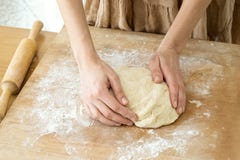 Ζύμη ζύμης που βρίσκονται σε έναν ξύλινο τέμνοντα πίνακα που ψεκάζεται με το αλεύρι, και χέρια γυναικών στοκ εικόνα με δικαίωμα ελεύθερης χρήσης Ζύμη ζύμης που βρίσκονται σε έναν ξύλινο τέμνοντα πίνακα που ψεκάζεται με το αλεύρι, και χέρια γυναικών στοκ εικόνα με δικαίωμα ελεύθερης χρήσης