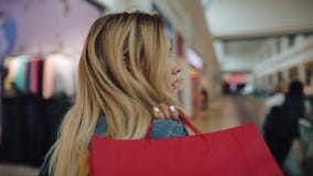 Η γοητεία της ξανθής γυναίκας κρατά τις τσάντες αγορών στον ώμο της περπατώντας γύρω από τη λεωφόρο απόθεμα βίντεο Η γοητεία της ξανθής γυναίκας κρατά τις τσάντες αγορών στον ώμο της περπατώντας γύρω από τη λεωφόρο απόθεμα βίντεο