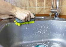 Η γυναίκα ` s καλλιέργησε τα πλυσίματα χεριών και καθαρίζει έναν νεροχύτη με ένα σφουγγάρι και μια βούρτσα στοκ εικόνες Η γυναίκα ` s καλλιέργησε τα πλυσίματα χεριών και καθαρίζει έναν νεροχύτη με ένα σφουγγάρι και μια βούρτσα στοκ εικόνες