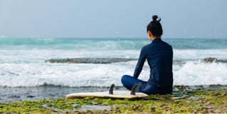 Η γυναίκα surfer κάθεται στο σκόπελο στοκ εικόνες Η γυναίκα surfer κάθεται στο σκόπελο στοκ εικόνες