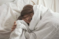 Η γυναίκα κάλυψε το πρόσωπό της με το μαξιλάρι. Εξέταση τη κάμερα. στοκ φωτογραφίες με δικαίωμα ελεύθερης χρήσης Η γυναίκα κάλυψε το πρόσωπό της με το μαξιλάρι. Εξέταση τη κάμερα. στοκ φωτογραφίες με δικαίωμα ελεύθερης χρήσης