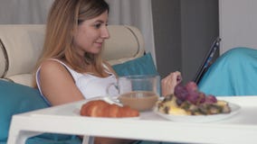 Η γυναίκα στο κρεβάτι χρησιμοποιεί ένα lap-top και κοντινός στο δίσκο της με τον καφέ και τα γλυκά προγευμάτων απόθεμα βίντεο Η γυναίκα στο κρεβάτι χρησιμοποιεί ένα lap-top και κοντινός στο δίσκο της με τον καφέ και τα γλυκά προγευμάτων απόθεμα βίντεο