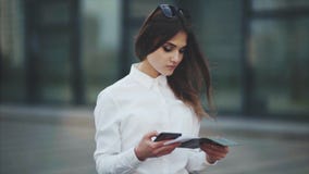 Η ελκυστική γυναίκα σε ένα άσπρο πουκάμισο, ελέγχει τα εισιτήρια για το αεροπλάνο, το τραίνο ή το λεωφορείο Το κορίτσι προσπαθεί απόθεμα βίντεο Η ελκυστική γυναίκα σε ένα άσπρο πουκάμισο, ελέγχει τα εισιτήρια για το αεροπλάνο, το τραίνο ή το λεωφορείο Το κορίτσι προσπαθεί απόθεμα βίντεο