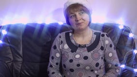 Η ευγενής μέσης ηλικίας γυναίκα με Άγιο Βασίλη ΚΑΠ χαμογελά και χορεύει φιλμ μικρού μήκους Η ευγενής μέσης ηλικίας γυναίκα με Άγιο Βασίλη ΚΑΠ χαμογελά και χορεύει φιλμ μικρού μήκους