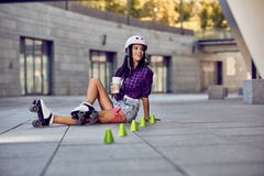 Η ευτυχής rollerblading συνεδρίαση εφήβων στην οδό και πίνει τον καφέ στοκ φωτογραφία με δικαίωμα ελεύθερης χρήσης Η ευτυχής rollerblading συνεδρίαση εφήβων στην οδό και πίνει τον καφέ στοκ φωτογραφία με δικαίωμα ελεύθερης χρήσης