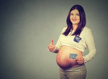 Η ευτυχής έγκυος γυναίκα με το δόσιμο χαπιών φυλλομετρεί επάνω στοκ φωτογραφία Η ευτυχής έγκυος γυναίκα με το δόσιμο χαπιών φυλλομετρεί επάνω στοκ φωτογραφία